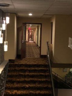 an empty hallway with stairs leading up to the rooms on each side and lights hanging from the ceiling