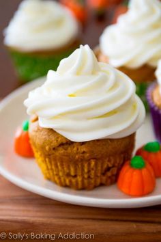 some cupcakes with white frosting and carrots on top are sitting on a plate