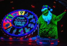 a man dressed as the grinch in front of a wheel of fortune at night