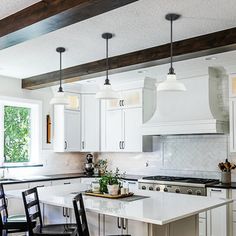 a kitchen with white cabinets and an island in the middle, surrounded by black chairs