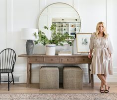 a woman standing in front of a table with two chairs and a mirror on it