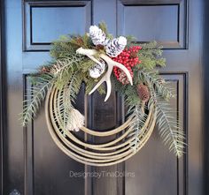 a wreath with pine cones, berries and antlers hangs on the front door