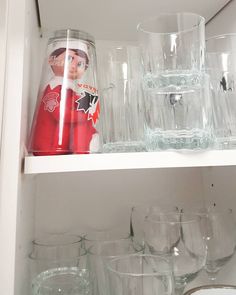 the shelves are filled with glassware and wine glasses, including one that has a doll on it