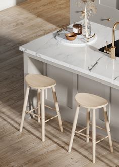 two stools sit on the counter in front of an island with marble top and gold faucet