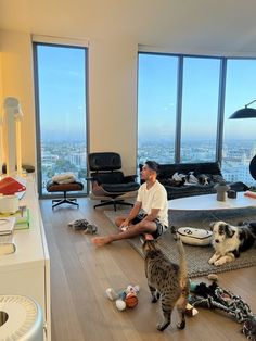 a man sitting on the floor with two cats and a dog in front of him