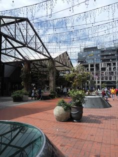 people are walking around in an open area with lots of plants and buildings behind them