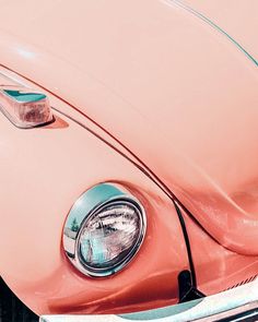 the front end of an old pink car