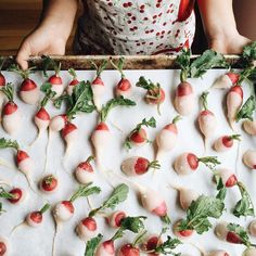 a child is holding a tray full of small fruits and veggies on it