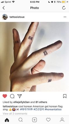 two fingers that have tattoos on them and one has the letter m in it's middle