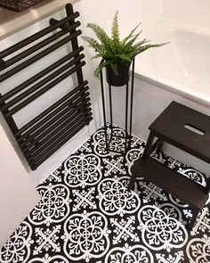 a black and white tiled bathroom with a plant in the corner next to the radiator