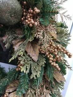 a christmas wreath with gold and green decorations on the outside of a window sill