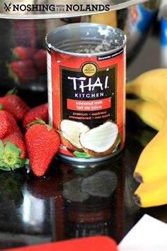 a can of thai kitchen fruit on a counter with bananas and strawberries next to it