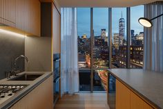 an apartment kitchen with a view of the city at night from it's windows