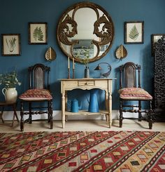 a blue room with two chairs and a table in front of a mirror on the wall