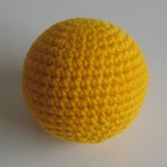 a yellow crocheted ball sitting on top of a white table