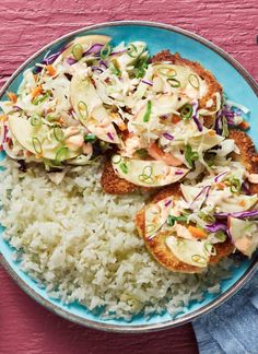 a blue plate topped with rice covered in coleslaw and crab cakes on top of it