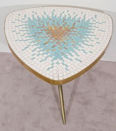 a table that has some kind of mosaic design on it, with gold legs and a blue center piece