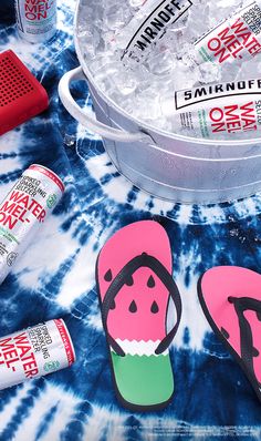 an ice bucket and some flip flops on a tie - dyed tablecloth with other items