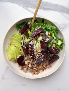 a salad with beets, lettuce and nuts in a white bowl on a marble table