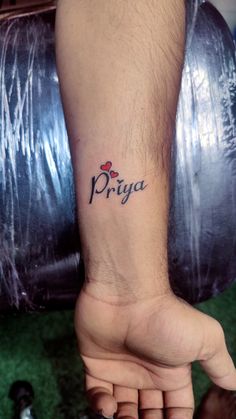 a person with a small tattoo on their arm and wrist, holding the word priya