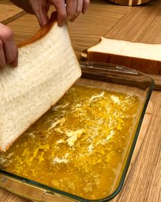 a person is spreading cheese on bread in a baking dish with mustard and bread slices next to it