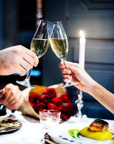 two people toasting with wine glasses at a dinner table