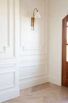 an empty room with white walls and wood flooring in the foreground is a light fixture