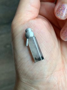 a person's hand holding a tiny silver object with glitters on it,