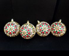 three ornaments are sitting next to each other on a black surface with red, green and yellow designs