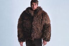 a man in a fur coat standing on a white background with his hands in his pockets