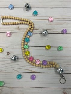 a wooden beaded necklace with various colored buttons and beads around it on a white wood surface