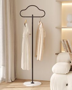 a coat rack with two coats hanging on it's sides next to a white chair