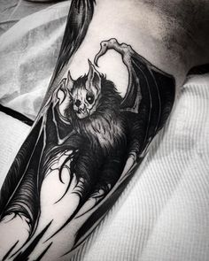 a man's arm with a bat tattoo on it, and an image of a demon