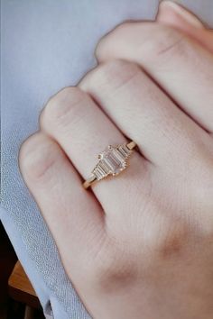 a woman's hand wearing a gold ring with three stones on the middle and one stone in the middle