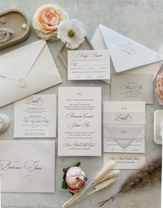 the wedding stationery is laid out with flowers, feathers and other things to put on it