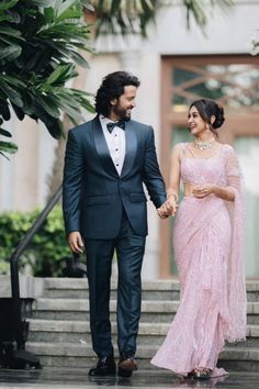 a man in a tuxedo and a woman in a pink dress holding hands