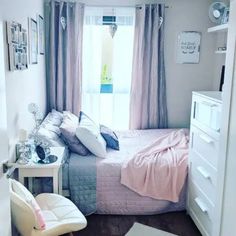 a bed room with a neatly made bed next to a dresser and chair in front of a window