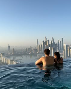 two people are sitting in the water near a city