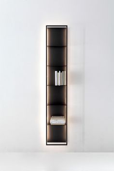 a book shelf with books and magazines on it in the corner of a white room