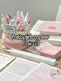 a desk topped with notebooks and pens next to a pink bag filled with writing