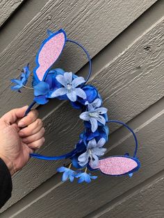 a hand is holding a blue and pink wreath