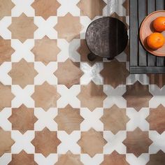 two oranges are sitting on a table in front of a black and white tiled wall