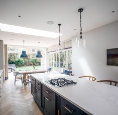 a kitchen with an island, stove and dining room table in the backround