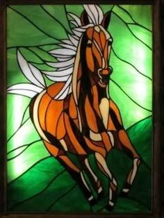 a stained glass window with a horse running in the grass