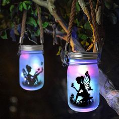 two mason jars with fairy lights hanging from the ceiling and one has a silhouette of tinkerbells on it