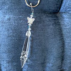 a glass beaded keychain hanging from a metal hook on a blue fabric