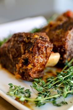 two pieces of meat on a plate with parsley garnishes and seasoning