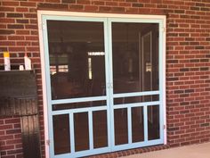 an open glass door in front of a brick building