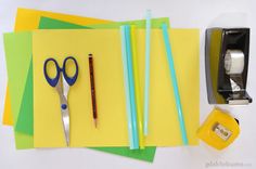 scissors, tape, and other craft supplies are laid out on top of yellow paper