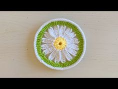 a crocheted dishcloth with a flower in the center on a wooden table